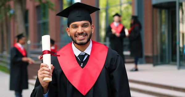 Young graduated boy holding his graduation degree convocation ceremony. Attractive multiracial student graduate posing towards the camera during the ceremony — Photo