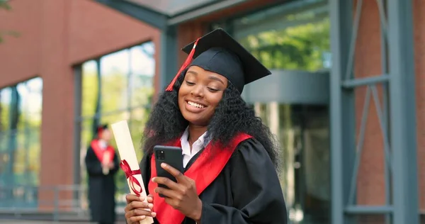 电子学习、教育和人的概念。笑容满面的多种族女研究生站在街头，拿着智能手机，笑容满面地打字 — 图库照片
