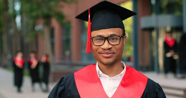 Jovem graduado realizando sua cerimônia de convocação grau de graduação. Estudante multirracial atraente graduado posando para a câmera durante a cerimônia — Fotografia de Stock