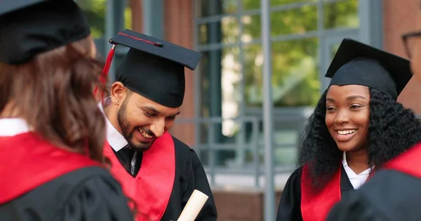 Company of happy multiracial student people are celebrating their graduation while standing near the college and rejoicing with diplomas at the hands. Education concept — Photo