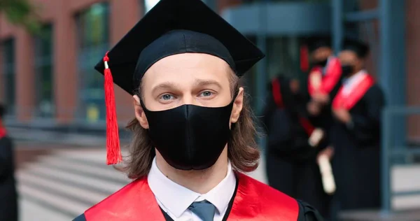 Portraitaufnahme des kaukasischen männlichen Studenten mit schwarzem Hut, der vor der Kamera posiert, weil er sein Studium abgeschlossen hat. Bildungskonzept — Stockfoto