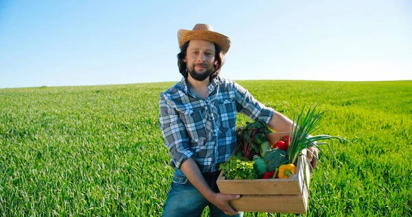 Blanke vermoeide boer met hoed die het platteland uitloopt met verse, verzamelde groene groenten. Voedsel oogsten. Binnenlandse landbouwindustrie. Biologisch voedselconcept — Stockfoto