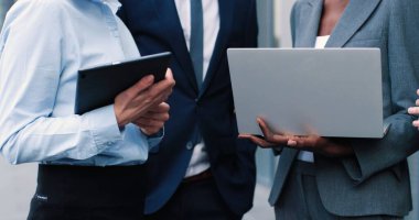 Proje yazma. Takım elbiseli neşeli, başarılı yetişkin iş ortakları dizüstü bilgisayara gülümseyerek bakıyor. Sokakta duruyorlar ve aletler üzerinde çalışıyorlar.