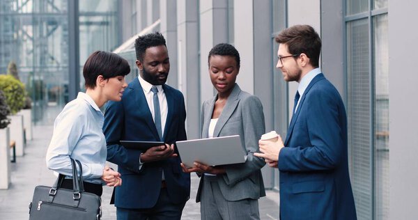Портрет деловой женщины с ноутбуком и беседой с коллегами. Один из людей внимательно слушал, когда пил кофе. Они улыбаются, смотрят друг на друга.