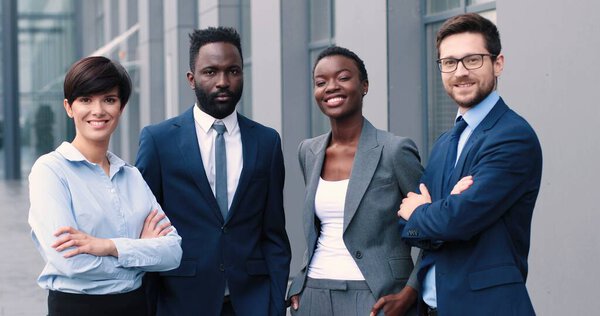 Сделай паузу. Вверх по талии портрет веселых бизнесменов, улыбающихся зубастыми, стоя, скрестив руки возле своего делового центра. Концепция бизнеса