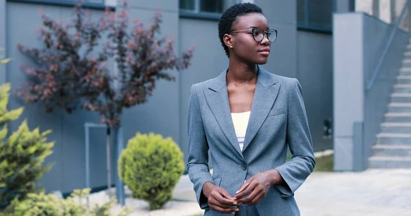 Visão de retrato da mulher multirracial confiante vestindo óculos e roupas formais alcançando sucesso de negócios e braços cruzados enquanto sorri para a câmera — Fotografia de Stock