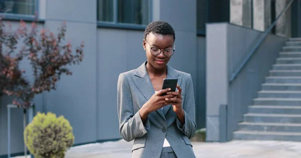 Affärssamtal. Midja upp porträtt av attraktiv ung kvinna i formella kläder har telefon samtal med meddelanden. Hon tittar på kameran med glada uttryck — Stockfoto