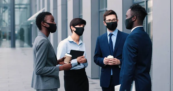 Ouçam com atenção. Jovens habilidosos e agradáveis empresários responsáveis de terno estão de pé na rua e olhando uns para os outros na pausa para o café. Conceito de negócio — Fotografia de Stock