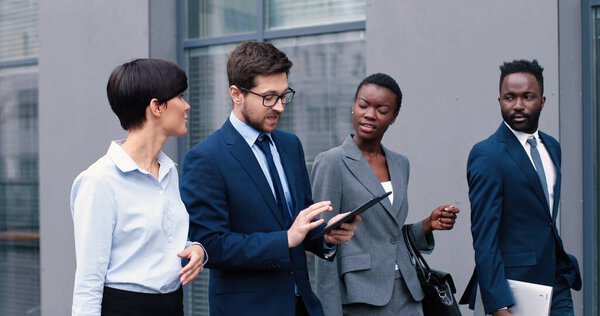 В пути. Талия до портрет зрения деловых людей, обсуждающих вместе о новом проекте во время прохождения по улице рядом с их бизнес-центром