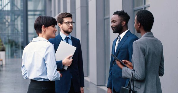 Концепция успешной командной работы. Портрет жизнерадостного бизнеса разнообразных коллег, стоящих на улице возле своего офиса и обсуждающих работу и планы