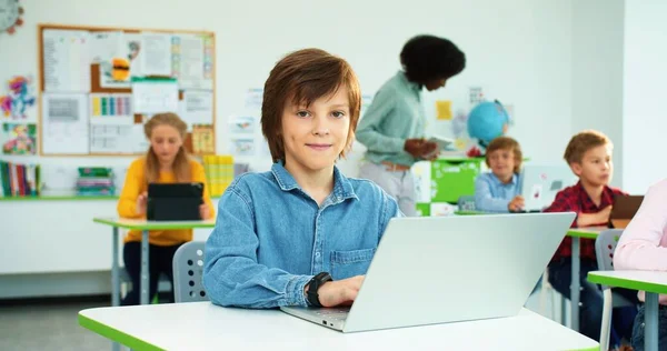 在小学学习的儿童。在计算机科学课上，白人女学生和男学生在笔记本电脑上打字的肖像- -非洲裔美国女教师在平板电脑后面敲打 — 图库照片