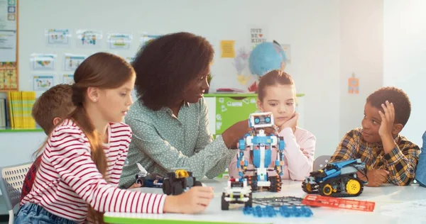 年轻美丽的非洲裔美国妇女在学校帮助多种族儿童制作玩具，学习机械。小学教师与初中学生在科学课上，近距离接触 — 图库照片