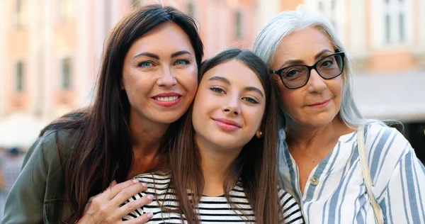 Drei Generationen. Porträtansicht der Seniorin, die ihre erwachsene Tochter und ihre Teenager-Enkelin umarmt, während sie während des Familienwochenendes in die Kamera blickt. Konzept zum Frauentag — Stockfoto