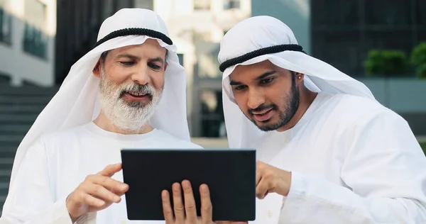 Obraťte se na portrét arabských obchodníků, jak spolu klábosí a dívají se na tabulku, zatímco stojí na ulici. Obchodní koncept — Stock fotografie