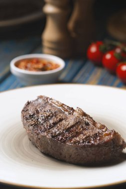 Izgara biftek, kiraz domatesleri ahşap masada tuz ve biber..