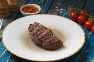 Izgara biftek, kiraz domatesleri ahşap masada tuz ve biber..