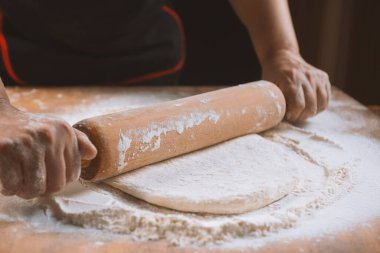 Pizza hazırlamak için hamur yoğuruyorum. Aşçı ahşap masada turta pişirmek için hamur yapıyor. İşlem hazırlığı ev yapımı hamur işi. Makarna, ekmek, spagetti, khachapuri, yemek konsepti.
