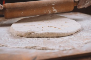 Pizza hazırlamak için hamur yoğuruyorum. Aşçı ahşap masada turta pişirmek için hamur yapıyor. İşlem hazırlığı ev yapımı hamur işi. Makarna, ekmek, spagetti, khachapuri, yemek konsepti.