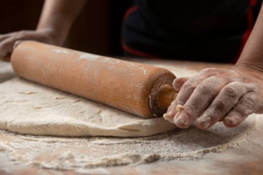 Pizza hazırlamak için hamur yoğuruyorum. Aşçı ahşap masada turta pişirmek için hamur yapıyor. İşlem hazırlığı ev yapımı hamur işi. Makarna, ekmek, spagetti, khachapuri, yemek konsepti.