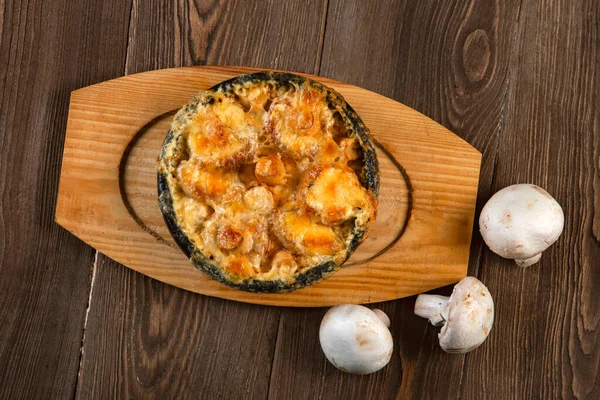Julienne in a pot and mushrooms on a wooden table. Mushrooms baked with cheese crust in pan .top view — Stock Image Julienne Pot Mushrooms Wooden Table Mushrooms Baked Cheese Crust Pan Royalty Free Stock Photos