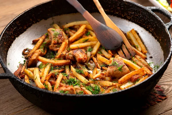 Demir bir tavada kızarmış et ve patates.