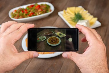 Yemek blogcusu akıllı telefon kullanarak fotoğraf çekiyor. Mans elleri geleneksel yemeklerin fotoğrafını çekiyor. Öğle ya da akşam yemeği. Sığır stroganoff. Sosyal medya ve blog için. Üst görünüm cep telefonu.