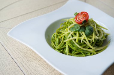 Tahta masada peynirli ve domatesli ıspanaklı spagetti.