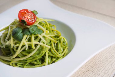 Tahta masada peynirli ve domatesli ıspanaklı spagetti.