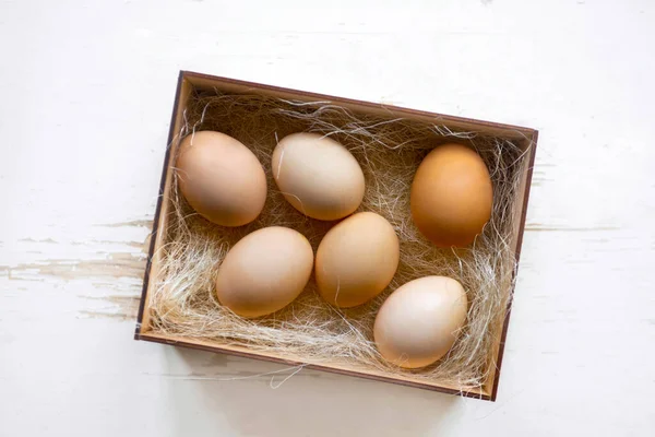 Eggs with hay in wooden box on rustic fabric. Top view food composition. Chicken eggs. Easter concept with copy space for text.Top view