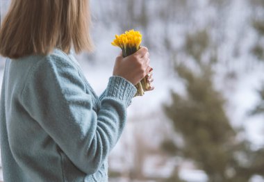 Bir buket sarı çiçeği tutan kadın