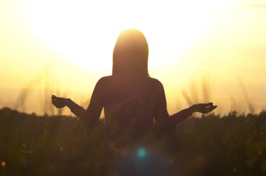 Gün batımında yoga yapan bir kadının arka ışığı.
