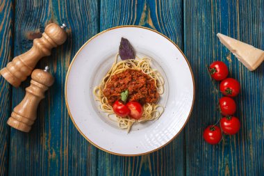 Etli makarna, domates sosu ve mavi ahşap masada sebzeler. en üstteki görünüm