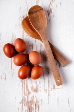 Beyaz ahşap arka planda yumurta ve tahta kaşıklar