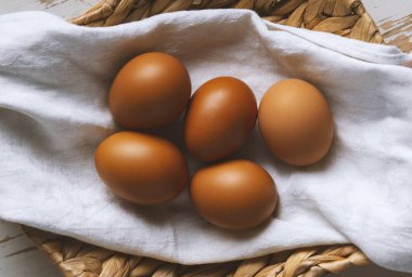Keten havluyla kaplanmış hasır sepetteki tavuk yumurtaları...