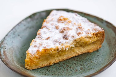 Beyaz ahşap zemin üzerinde seramik tabakta bir parça turta..