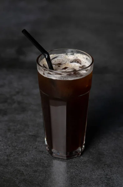 stock image Ice coffee in a tall glass over a. Cold summer drink on a dark background with copy space