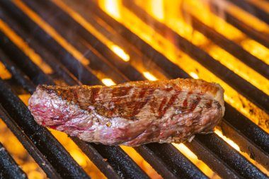 Izgarada alevler içinde biftek cızırdıyor.