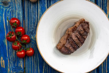Izgara biftek, kiraz domatesleri ahşap masada tuz ve biber..