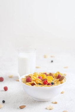 Böğürtlenli mısır gevreği, yabanmersini ve beyaz ahşap arka planda sütlü frenk üzümü.