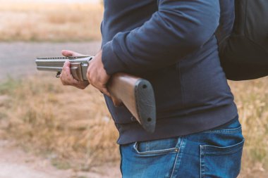 Erkek avcı av tüfeğiyle avlanmaya hazır. Avcı tüfeğini tutuyor..