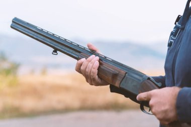 Erkek avcı av tüfeğiyle avlanmaya hazır. Avcı tüfeğini tutuyor..