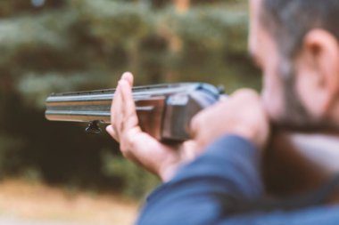 Erkek avcı av tüfeğiyle avlanmaya hazır. Avcı tüfeğini tutuyor..