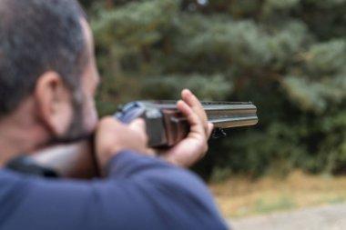 Erkek avcı av tüfeğiyle avlanmaya hazır. Avcı tüfeğini tutuyor..