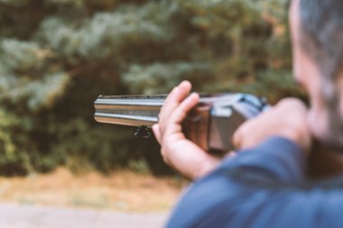 Erkek avcı av tüfeğiyle avlanmaya hazır. Avcı tüfeğini tutuyor..