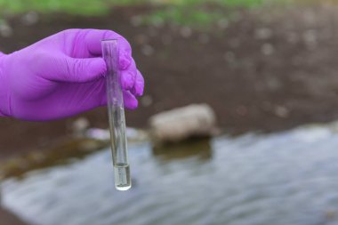 Analiz için nehirden örnek su. Bir test tüpü tutan eldiven. Ekoloji konsepti.