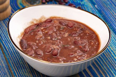 Kırmızı fasulyeli sağlıklı fasulye çorbası, mavi ahşap arka planda ev yapımı çorba, vejetaryen yemeği..