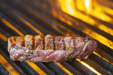 Izgarada alevler içinde biftek cızırdıyor.