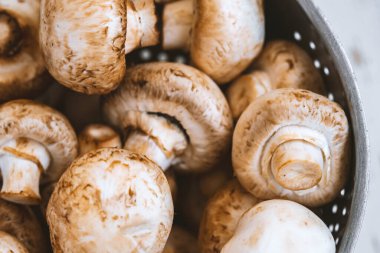 Beyaz ahşap arka planda demir bir kasede çiğ mantar.