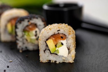 Pilavlı suşi, salatalık, avokado, somon, susam. Suşi menüsü. Japon yemeği..
