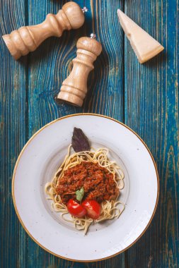 Mavi ahşap arka planda kıyma ve kiraz domatesli lezzetli spagetti. Üst manzara, düz uzanma